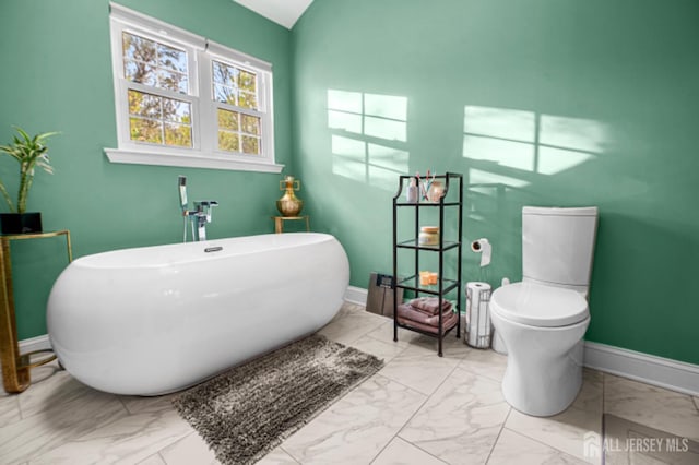 full bathroom with marble finish floors, a soaking tub, baseboards, and toilet