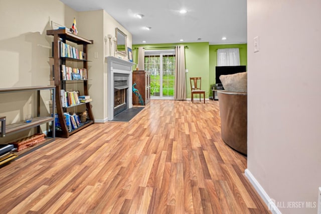 living room with wood finished floors, a fireplace with flush hearth, baseboards, and recessed lighting