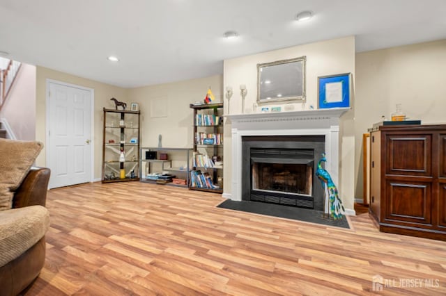 living area with stairs, wood finished floors, a fireplace with flush hearth, recessed lighting, and baseboards