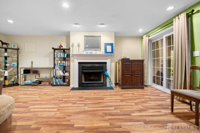 living area with wood finished floors, a fireplace with flush hearth, and recessed lighting