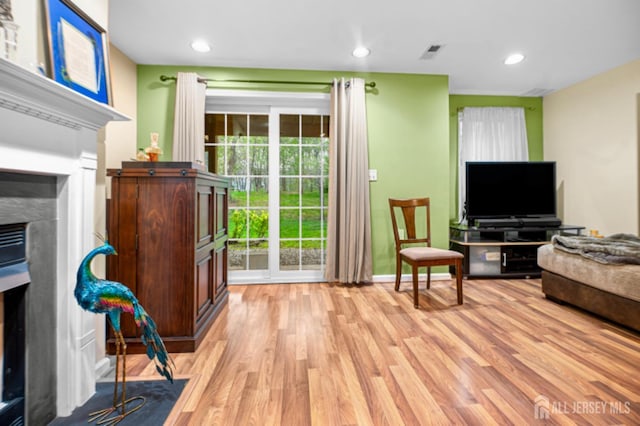 living room featuring a fireplace with flush hearth, light wood-style floors, recessed lighting, and baseboards