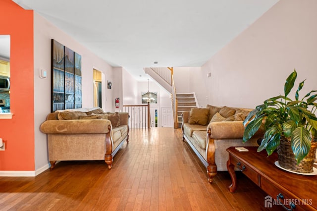 living area with wood-type flooring, baseboards, and stairs