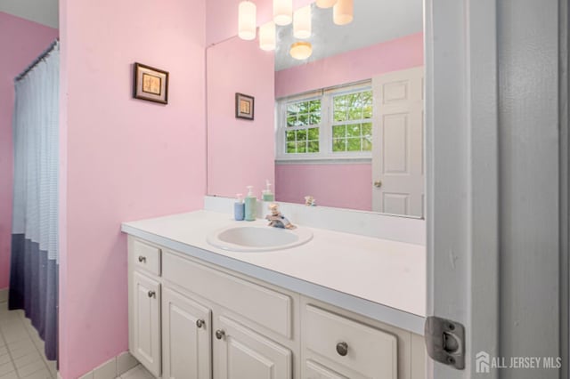 full bath featuring vanity, tile patterned floors, and baseboards
