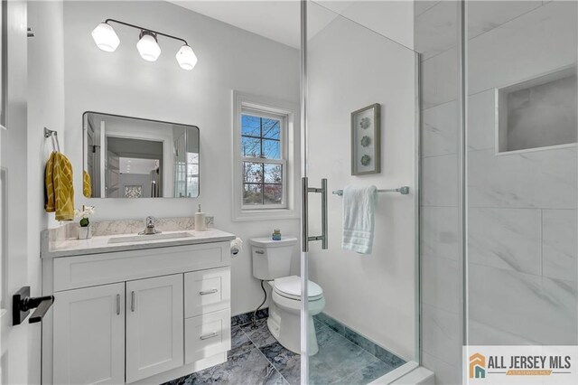 bathroom featuring vanity, a shower with door, and toilet