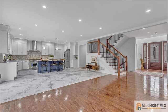 interior space featuring wall chimney exhaust hood, high end fridge, decorative light fixtures, a center island, and oven