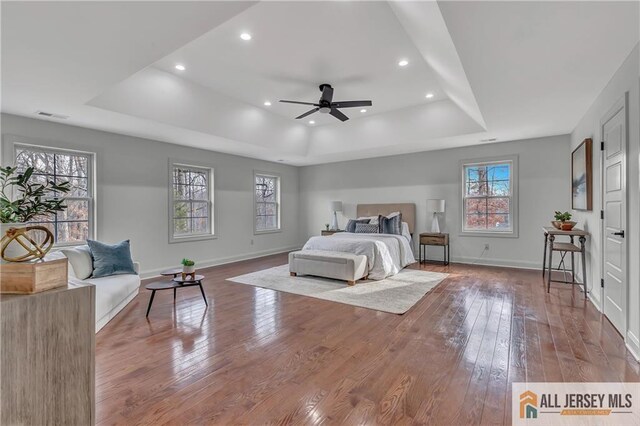 bedroom featuring ceiling fan, wood-type flooring, and a raised ceiling