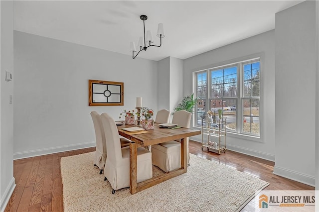 dining area with hardwood / wood-style flooring and a notable chandelier