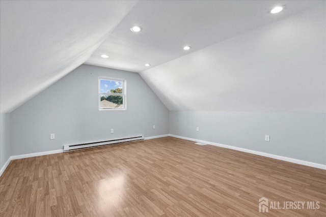 additional living space featuring vaulted ceiling, a baseboard heating unit, and light wood-type flooring