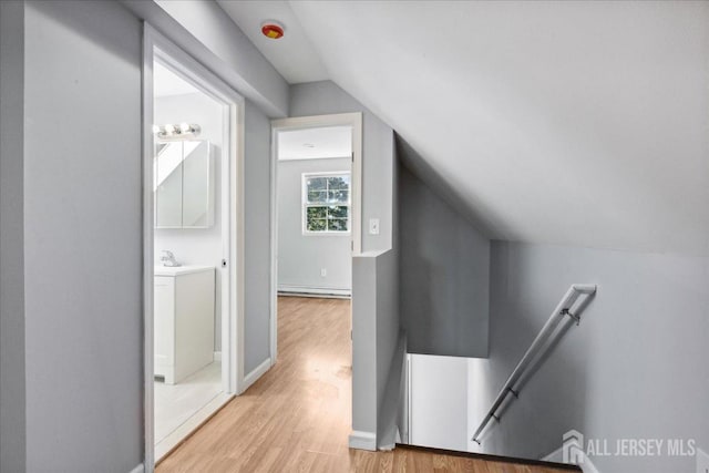 interior space featuring a baseboard heating unit, vaulted ceiling, and light wood-type flooring