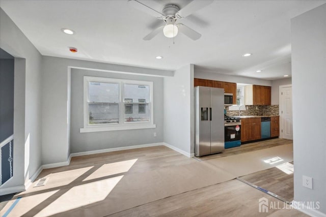 kitchen with sink, ceiling fan, appliances with stainless steel finishes, decorative backsplash, and light wood-type flooring