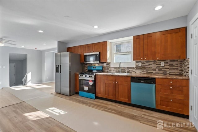 kitchen featuring sink, ceiling fan, backsplash, stainless steel appliances, and light hardwood / wood-style floors