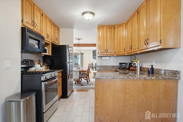 675 Raritan Rd, Clark, NJ 07066 - kitchen with black microwave, stainless steel gas stove, a peninsula, dark stone counters, and a sink