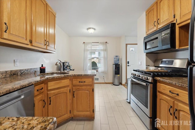 675 Raritan Rd, Clark, NJ 07066 - kitchen featuring appliances with stainless steel finishes, a sink, a peninsula, light wood-type flooring, and dark stone countertops