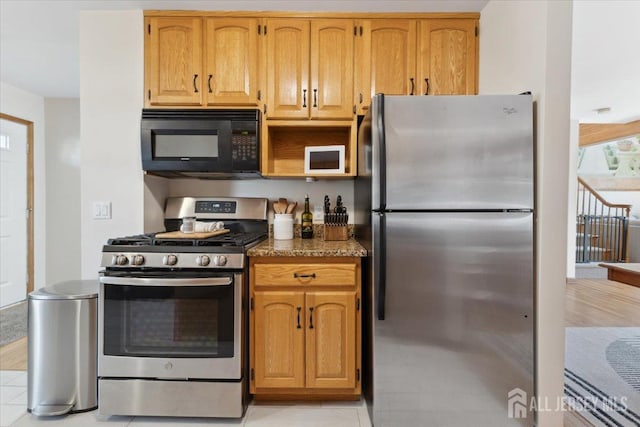 675 Raritan Rd, Clark, NJ 07066 - kitchen featuring stainless steel appliances, dark stone countertops, light tile patterned floors, and brown cabinets