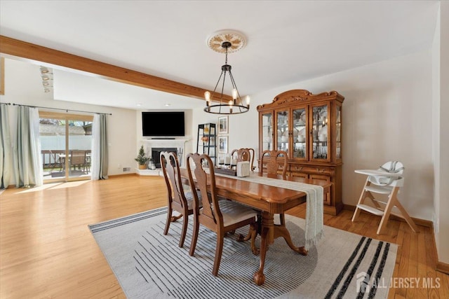 675 Raritan Rd, Clark, NJ 07066 - dining space with light wood-style floors, baseboards, a fireplace with raised hearth, and beam ceiling
