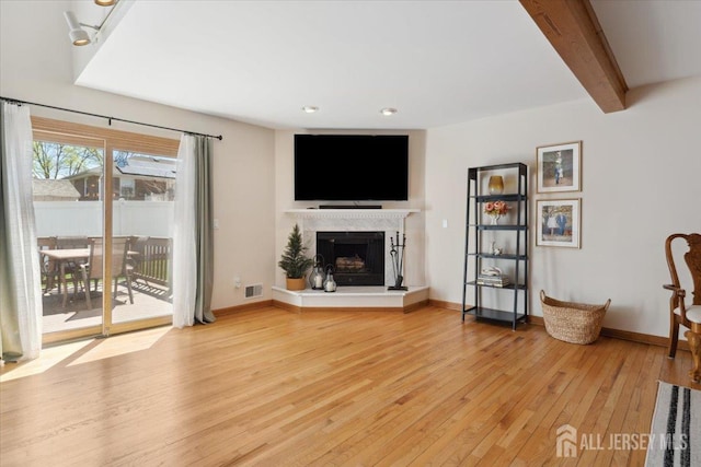675 Raritan Rd, Clark, NJ 07066 - living area featuring light wood-style flooring, a fireplace with raised hearth, beamed ceiling, baseboards, and recessed lighting