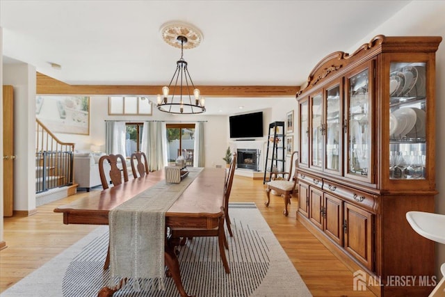 675 Raritan Rd, Clark, NJ 07066 - dining space featuring a chandelier, light wood-style flooring, a fireplace with raised hearth, and stairs