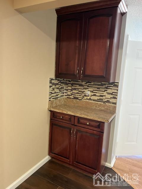bar with baseboards, backsplash, and dark wood-style flooring