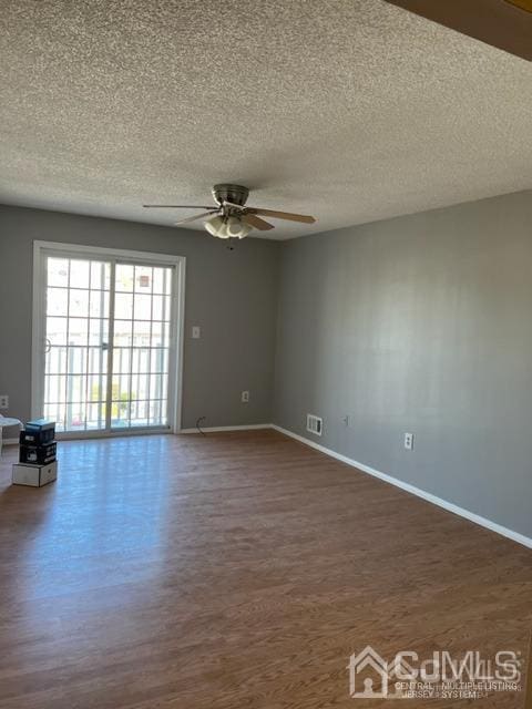 empty room with ceiling fan, baseboards, dark wood-type flooring, and a textured ceiling