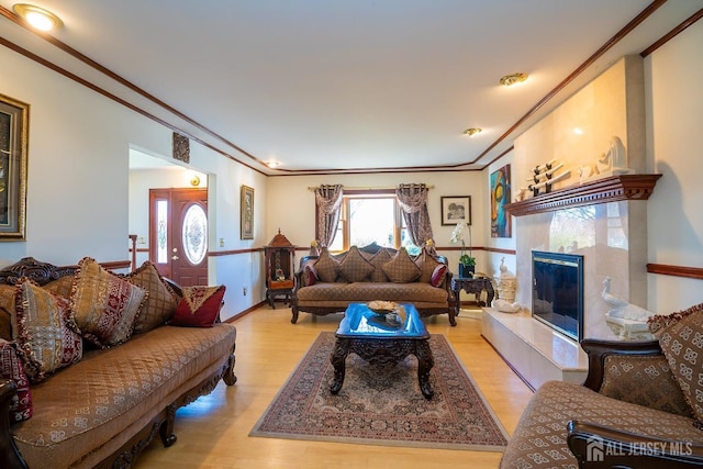 living room with light hardwood / wood-style floors, ornamental molding, and a fireplace