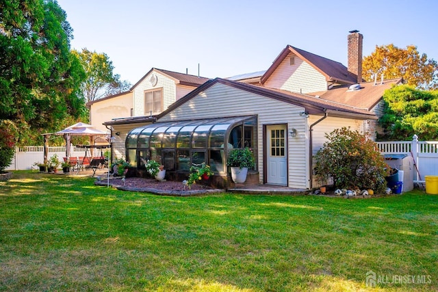 rear view of property with a sunroom, a patio area, and a yard