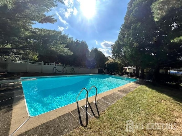 view of swimming pool with a diving board and a yard