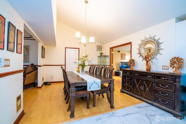 dining room featuring a chandelier, light wood-type flooring, and vaulted ceiling