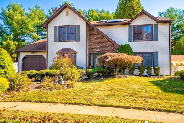 front of property with a front yard, solar panels, and a garage