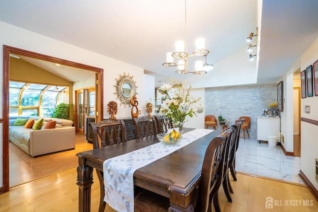 dining space with light wood-type flooring, lofted ceiling, and a chandelier