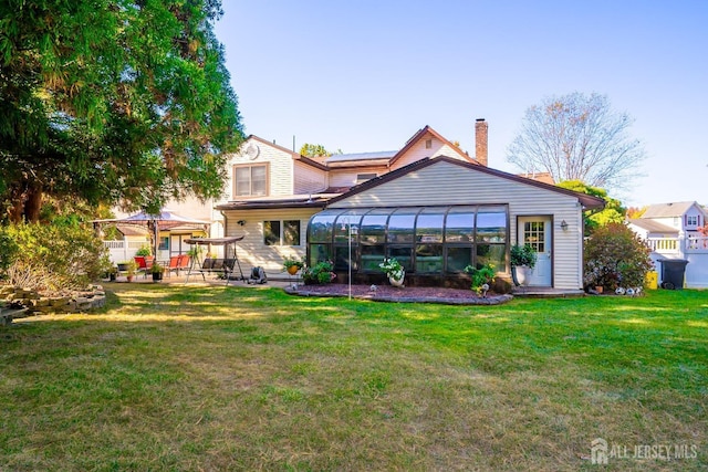 back of house featuring a sunroom and a yard