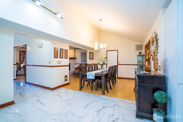 dining space with a notable chandelier, light wood-type flooring, and vaulted ceiling