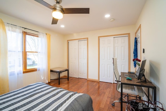 bedroom with ceiling fan, wood-type flooring, and multiple closets