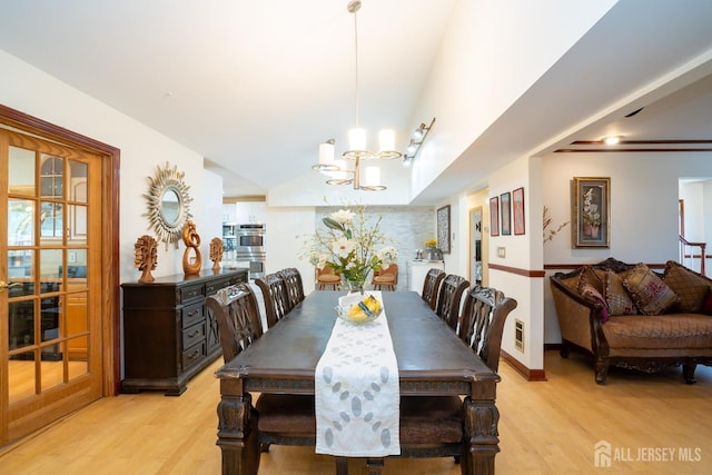 dining area with light hardwood / wood-style floors and an inviting chandelier