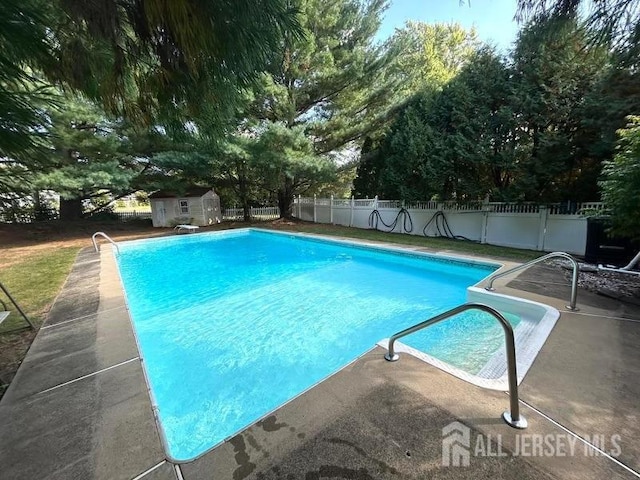 view of swimming pool featuring a patio area, a diving board, and a storage shed