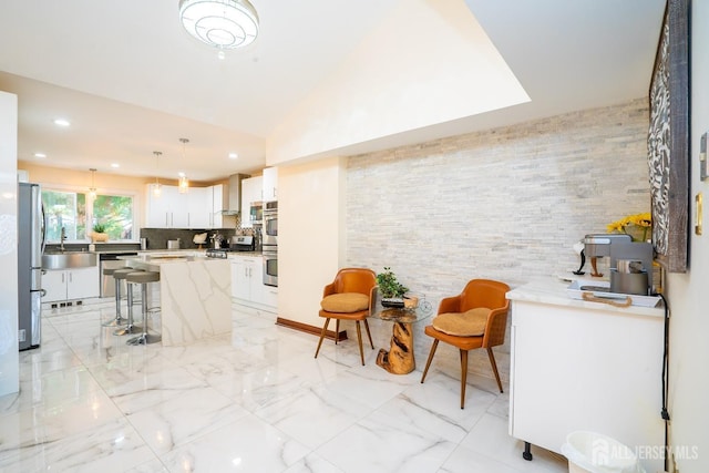 kitchen featuring appliances with stainless steel finishes, white cabinets, a center island, hanging light fixtures, and a breakfast bar area