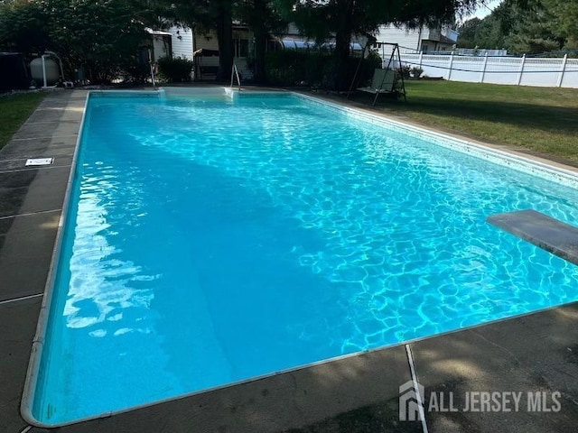 view of pool with a yard and a diving board