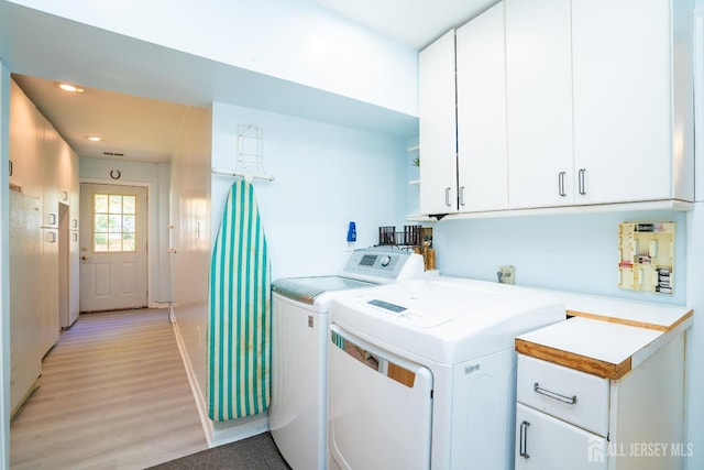 laundry room with cabinets, light wood-type flooring, and washer and clothes dryer