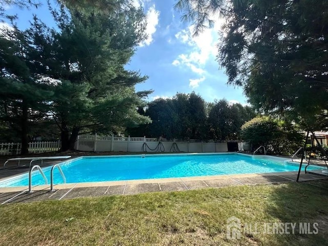 view of pool featuring a lawn and a diving board