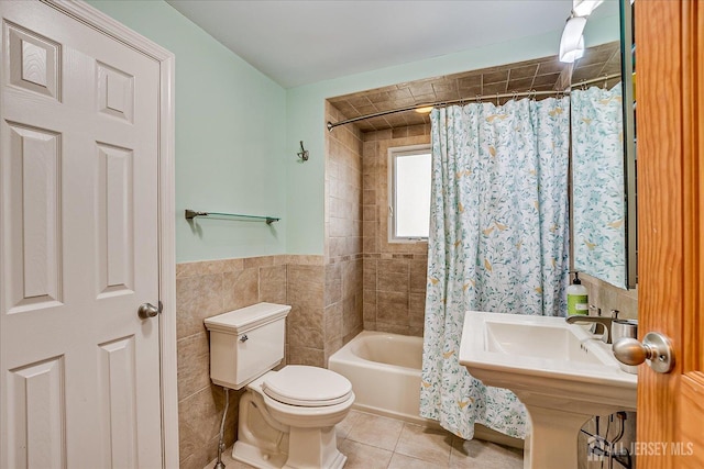 bathroom featuring toilet, shower / bath combo, tile patterned flooring, and tile walls