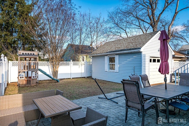 view of patio / terrace with a playground, a garage, and an outbuilding