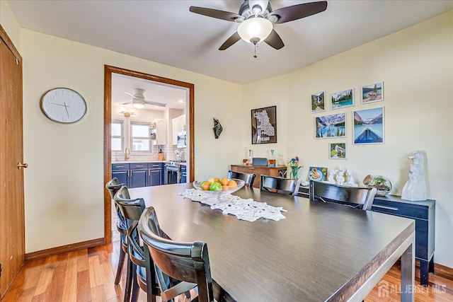 dining area with sink, light wood-type flooring, and ceiling fan