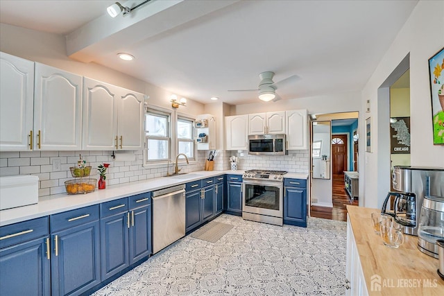 kitchen with sink, white cabinets, ceiling fan, blue cabinetry, and appliances with stainless steel finishes