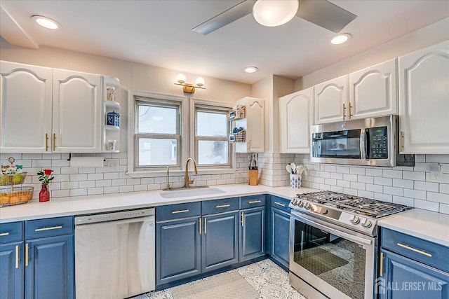 kitchen with tasteful backsplash, blue cabinets, white cabinets, appliances with stainless steel finishes, and sink