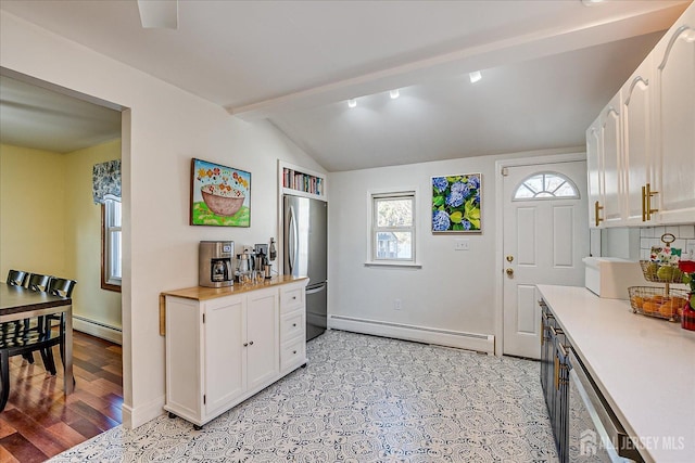 kitchen with stainless steel refrigerator, a baseboard radiator, lofted ceiling with beams, and white cabinetry