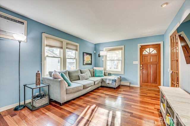 living room featuring a wall unit AC, a baseboard heating unit, and light hardwood / wood-style flooring