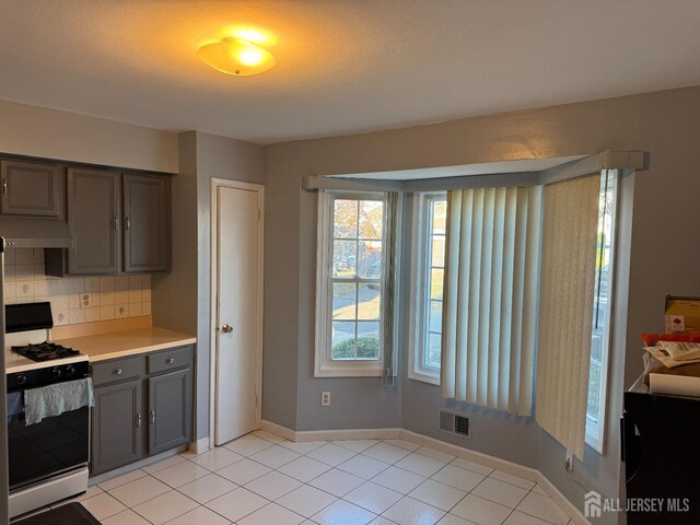 kitchen featuring backsplash, a textured ceiling, white range oven, light tile patterned floors, and range hood