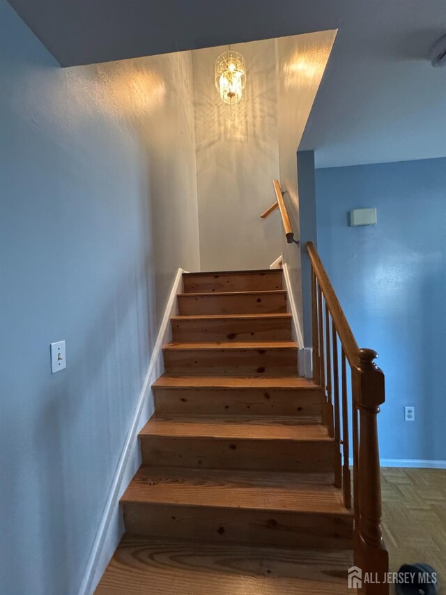 stairway with parquet flooring and a chandelier