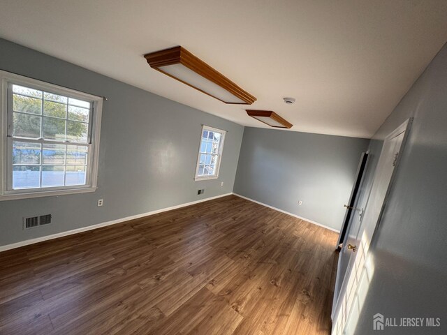 spare room featuring dark hardwood / wood-style floors, vaulted ceiling, and a wealth of natural light