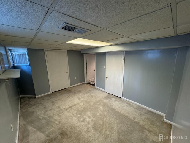 basement with a drop ceiling and light colored carpet