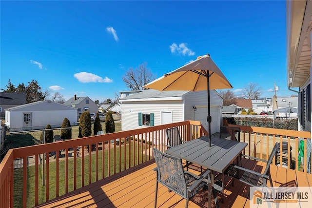 wooden terrace featuring an outbuilding, outdoor dining area, a lawn, and a residential view